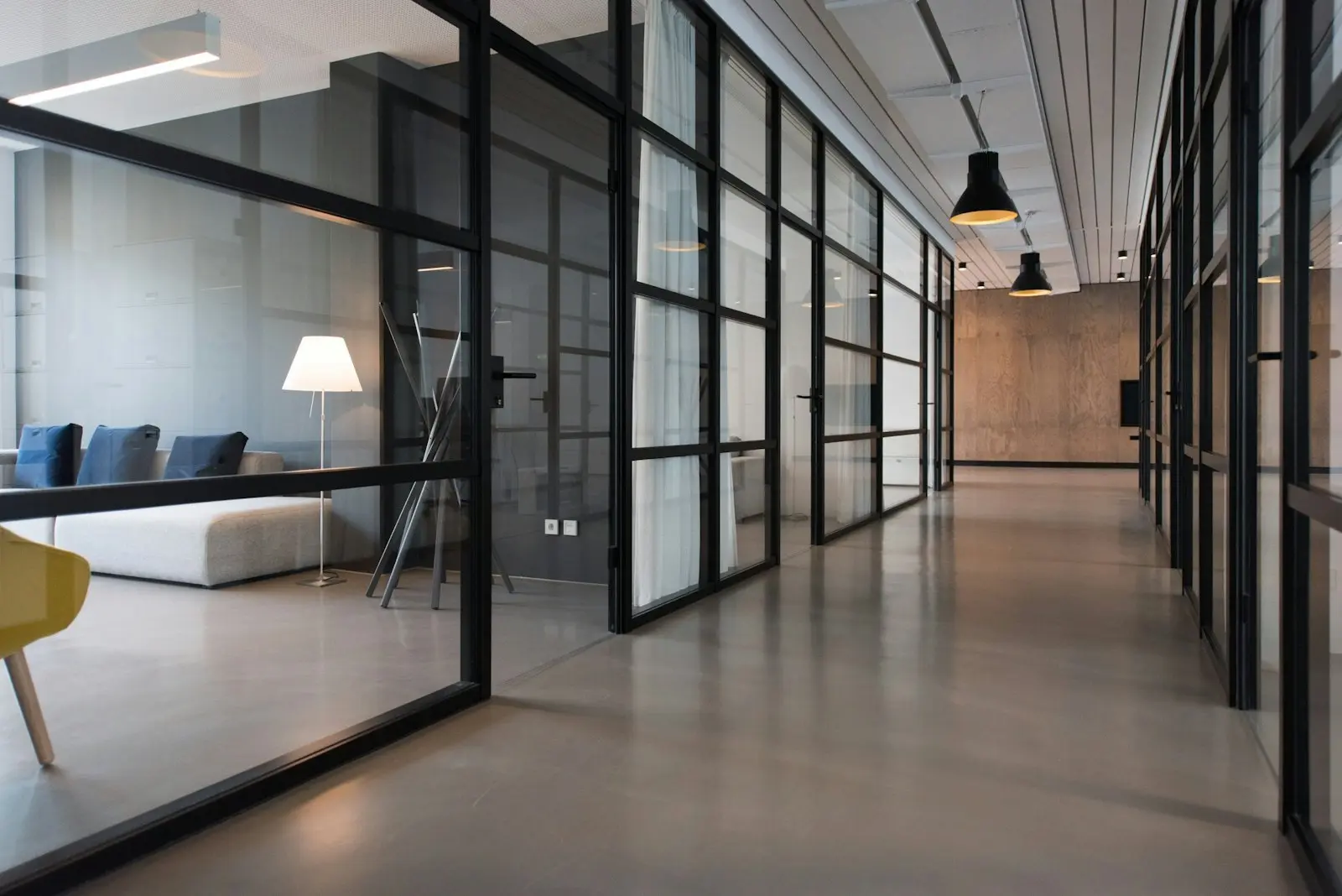 A modern office interior with glass partitions and a quiet corridor